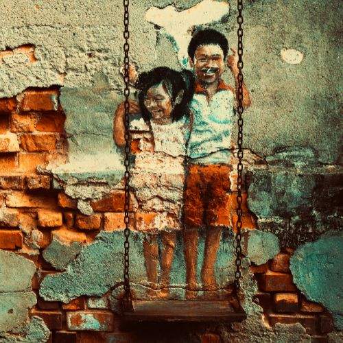 Penang street art with two children in a swing on wall
