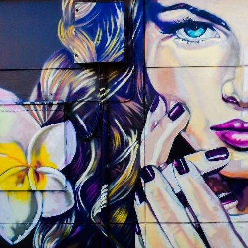 Wall graffiti of young lady with a white and yellow flower on the side